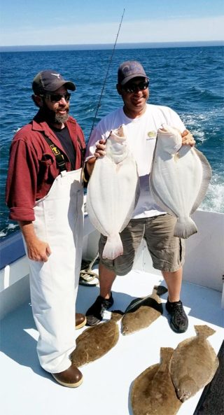two fishermen holding two flukes and four more on the deck